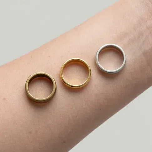An antiqued gold, a polished gold and a matte silver band resting on bare skin