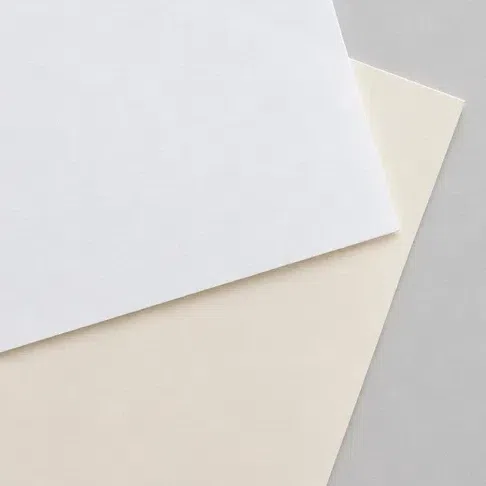 A sheet of pure optic white paper overlapping a warm ivory sheet