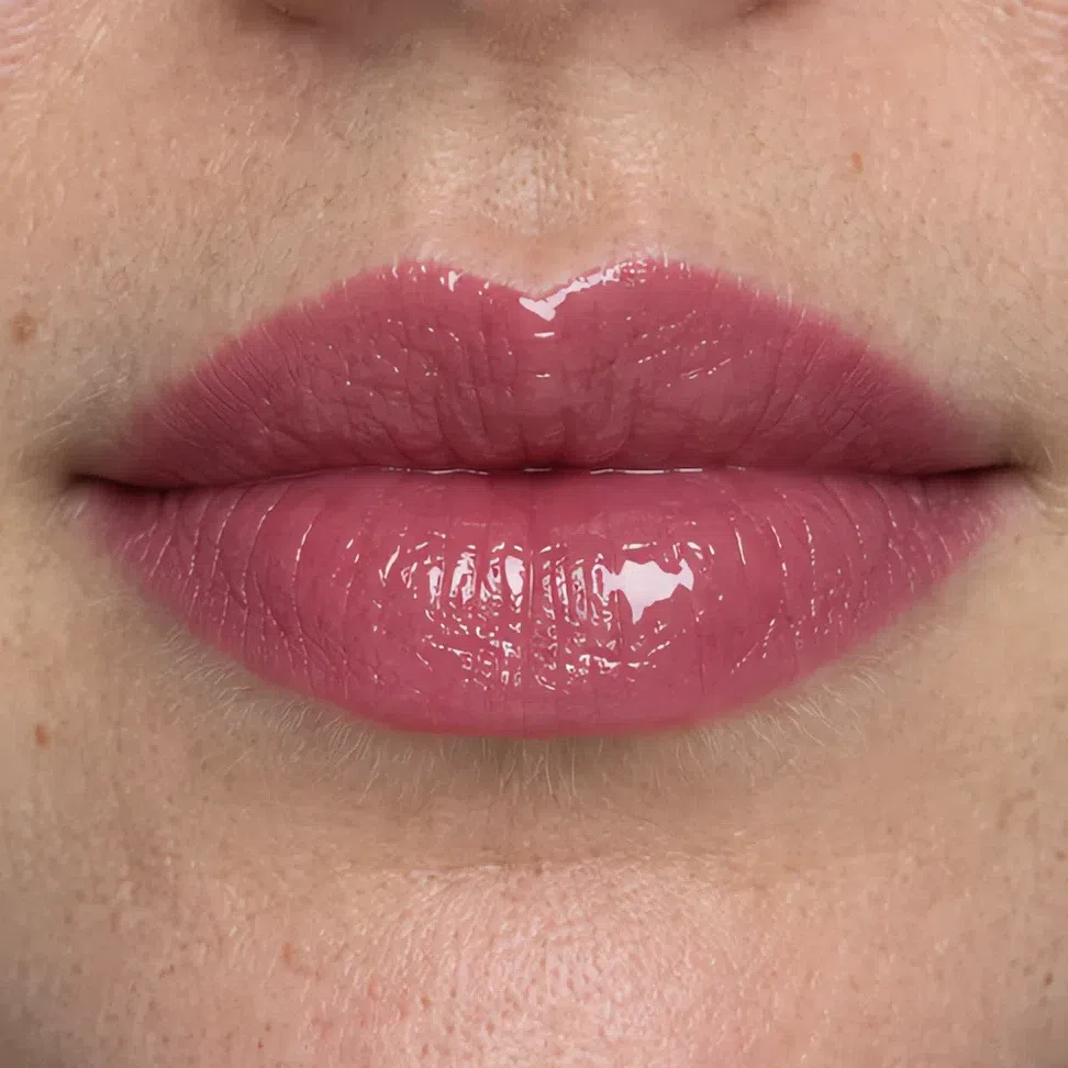 The same lipstick under a high gloss, the light source reflected in one bright point