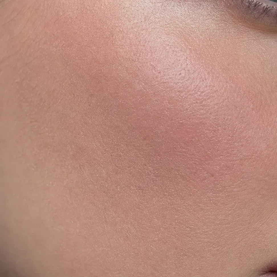 Cream blush worked into the cheek, the skin texture reading through the color
