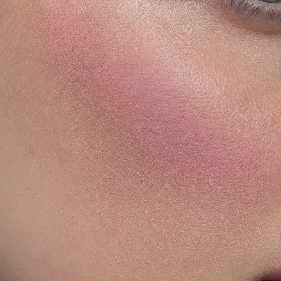 Powder blush resting on the surface of the cheek as a separate dusty layer