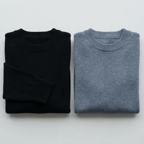 A jet black knit sweater beside a soft blue-gray graphite one