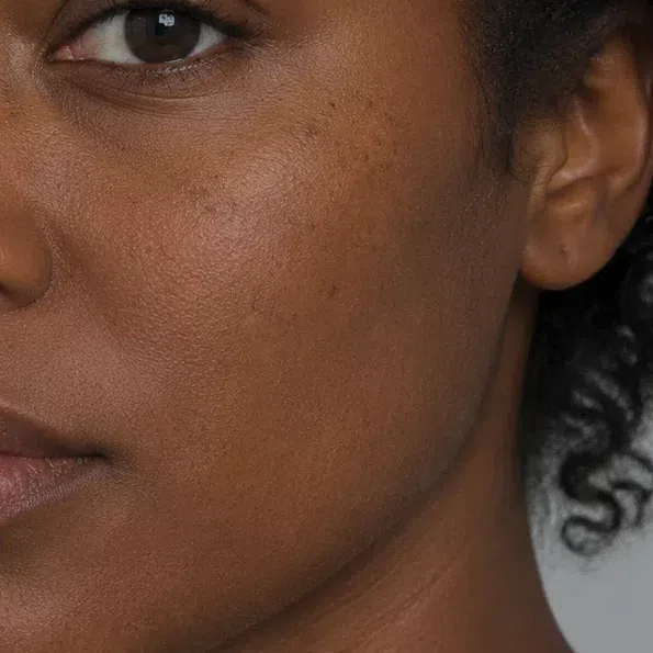 Deep brown cheekbone in close-up, a few soft freckles and a hint of terracotta