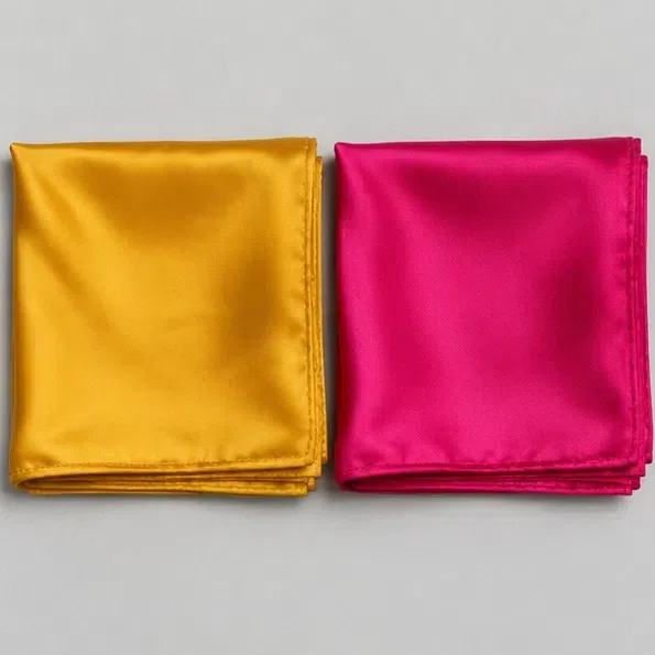 A mustard yellow silk kerchief folded beside a cold fuchsia one