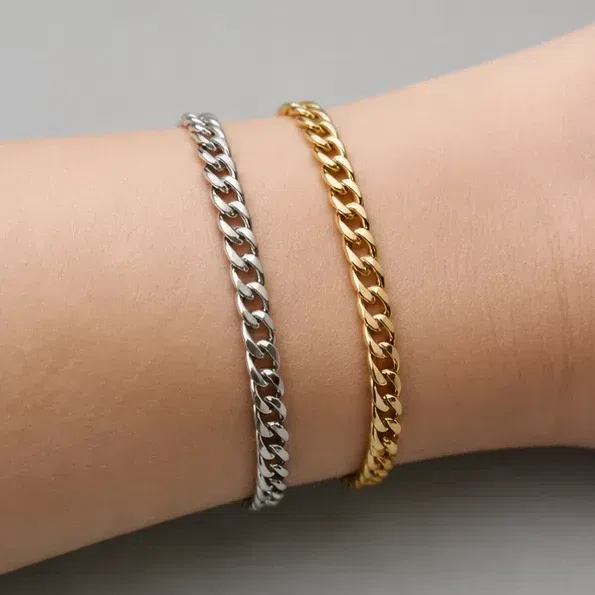 Two chain bracelets, silver and gold, worn together on one wrist