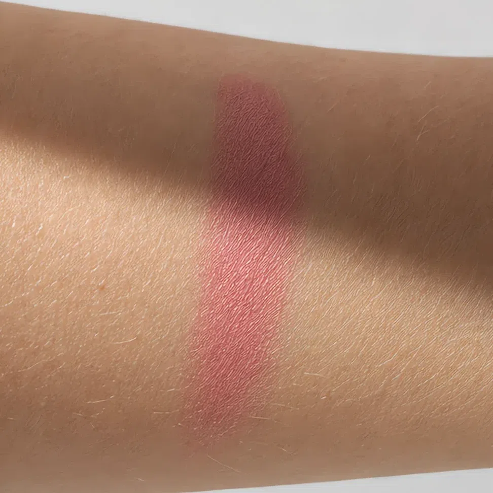 A cool rose swatch in soft daylight with a shadow across it, reading true