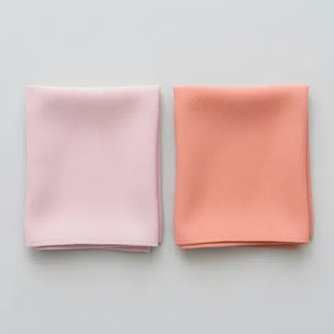 A cool rose pink fabric square beside a warm peach coral one