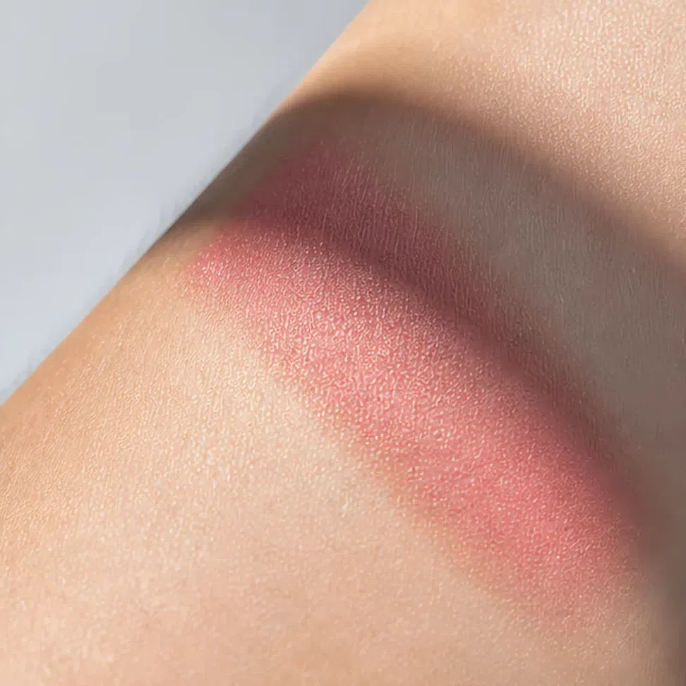 A dusty rose swatch in soft daylight with a shadow across it, reading muted