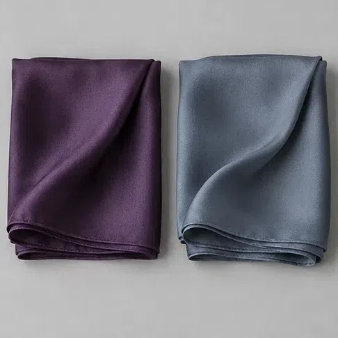 A rich plum silk scarf beside a smoky blue one