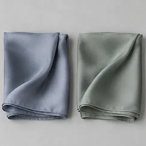 A clear gray-blue silk scarf beside a soft dusty sage one