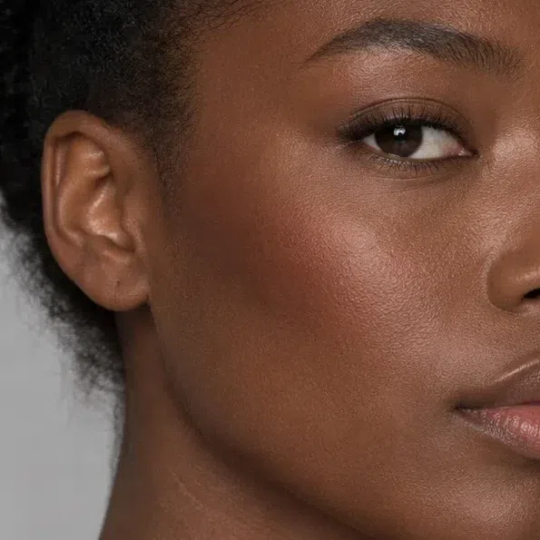 Close crop of deep brown skin glowing with a dark copper bronzer