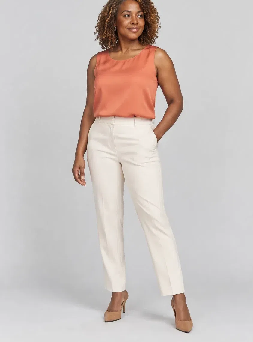 A deep-complexion Warm Spring woman in a coral-orange silk top and cream trousers