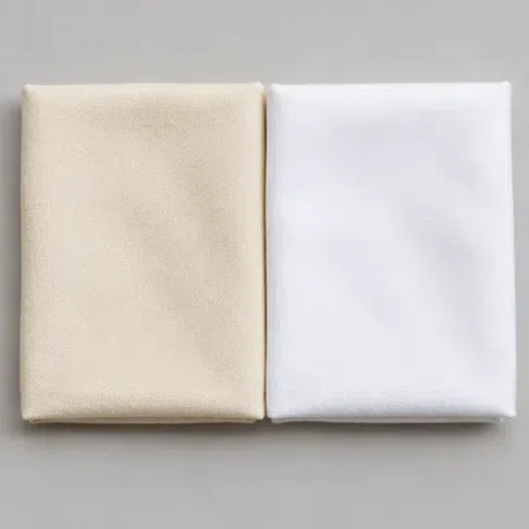 A warm cream cotton square beside a stark optic white one