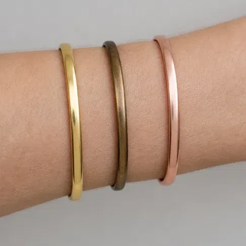 Yellow gold, bronze and rose gold bangles resting on bare skin